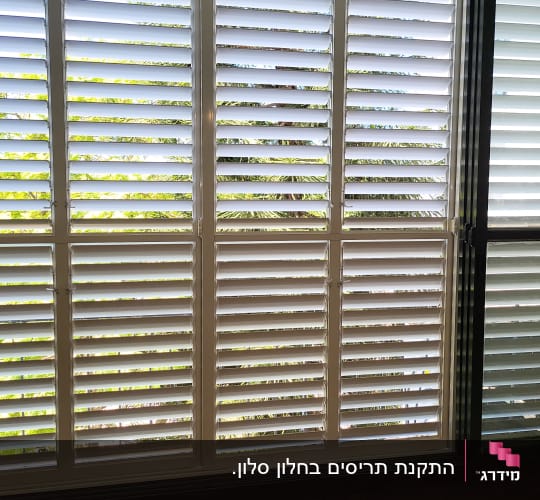 תריסי אלומיניום לבנים על חלון גדול